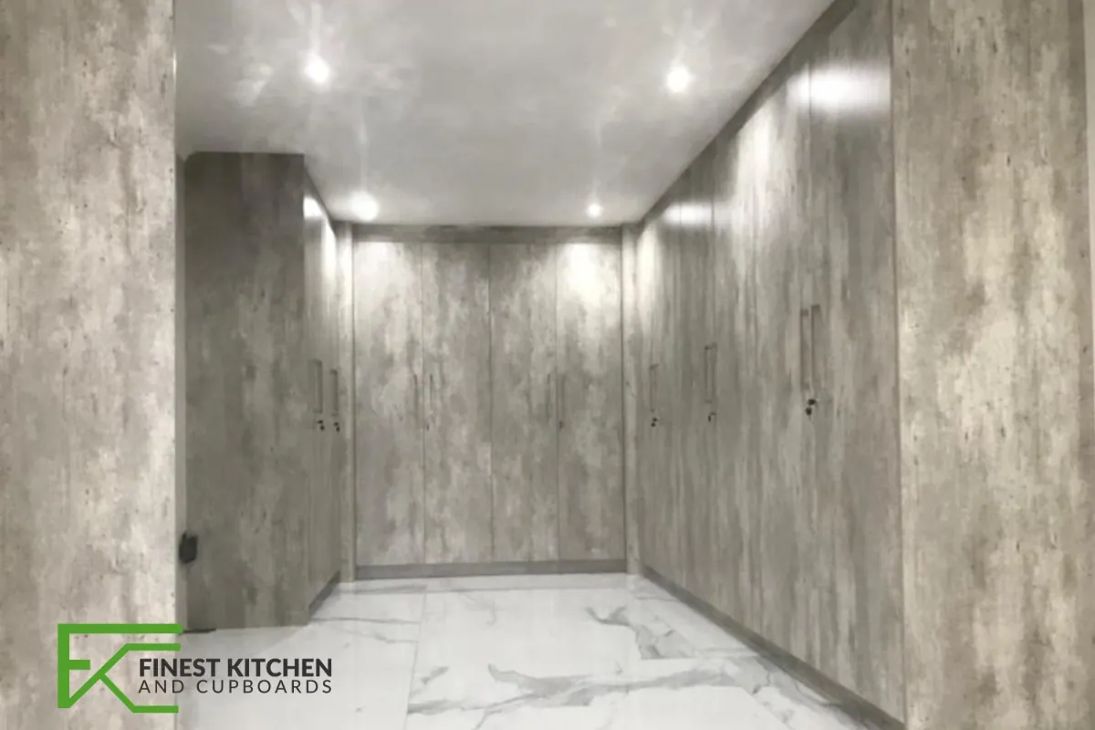 An FKC built-in cupboard run in white set against a concrete-look feature wall.