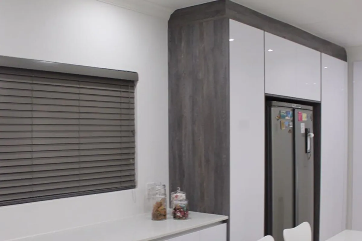 The tall unit run housing the fridge, finished in dark timber.