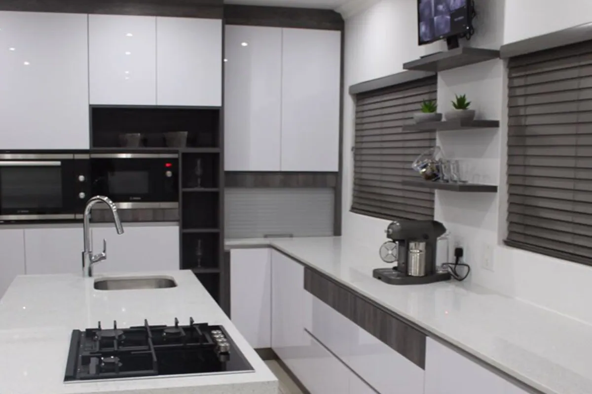 The hob run, with a gas hob set into white units below dark timber open shelving.