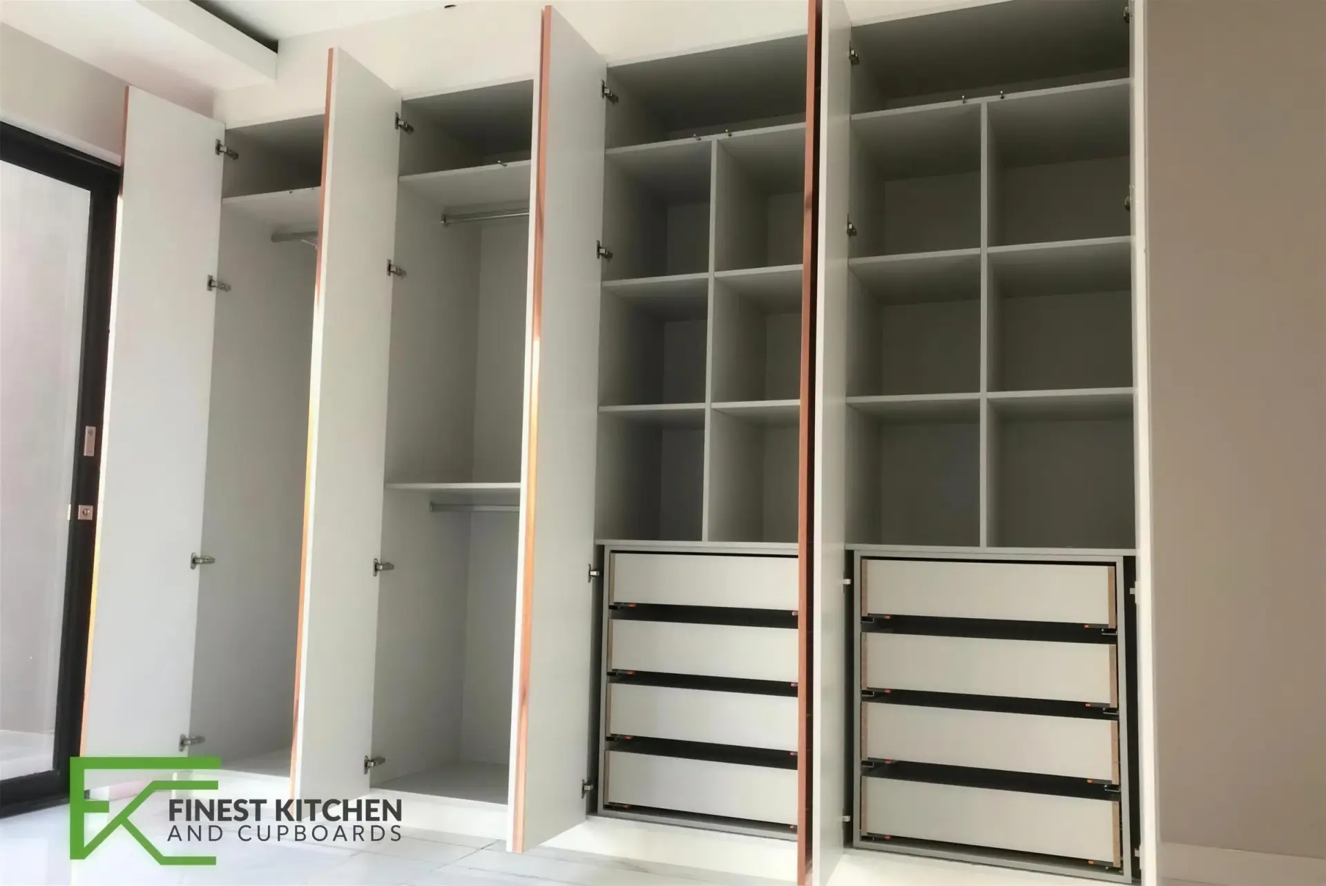 A white FKC built-in walk-in wardrobe with open shelving and drawers.