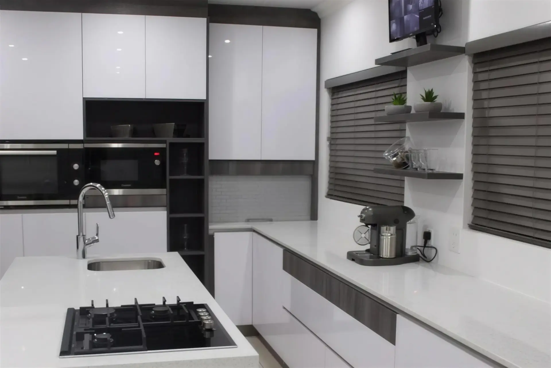 Kitchen Units 03: A white gloss kitchen with a black oven stack, dark timber shelving and an island with seating.