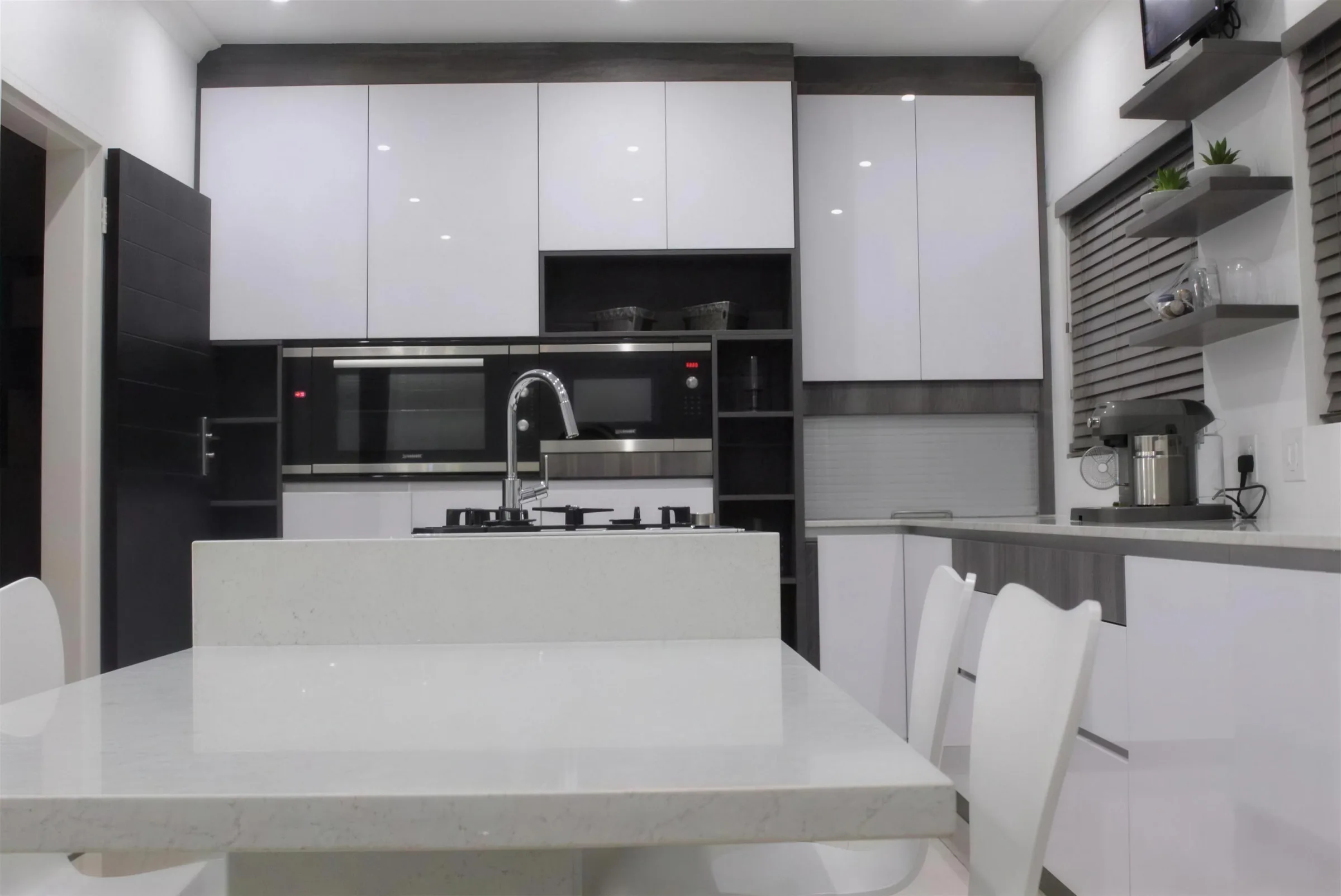 Kitchen Units 03: A white gloss kitchen with a black oven stack, dark timber shelving and an island with seating.