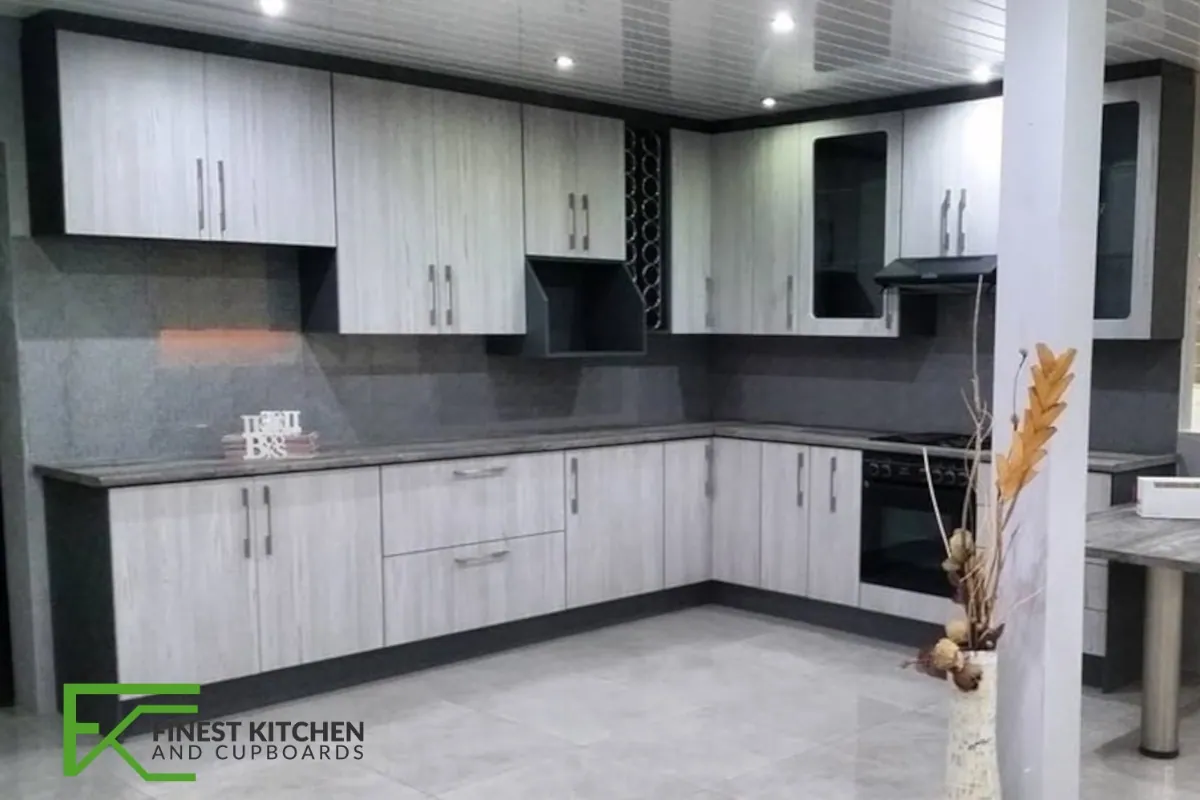 An L-shaped FKC kitchen in light timber and white, with a black oven stack built into a full-height run.