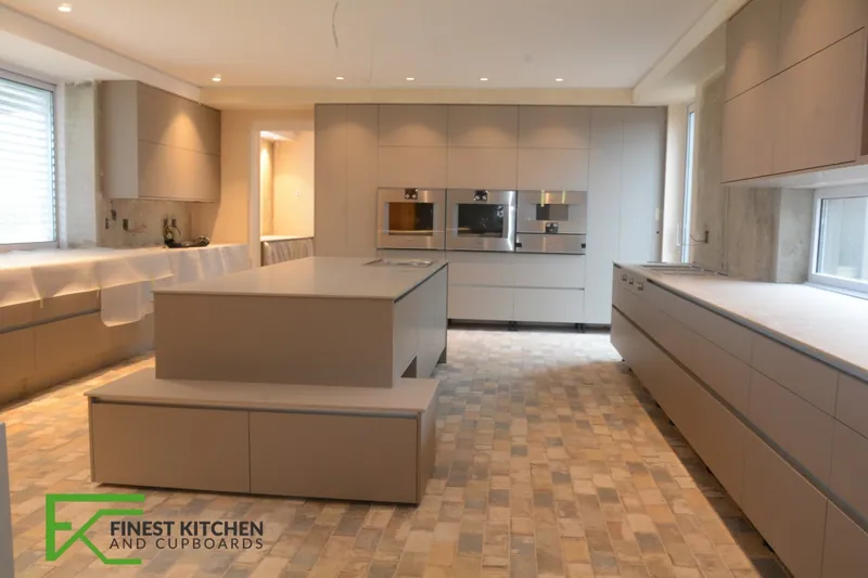 A long galley kitchen in cream and white opening onto a wood-floored dining area, built by FKC Kitchens.