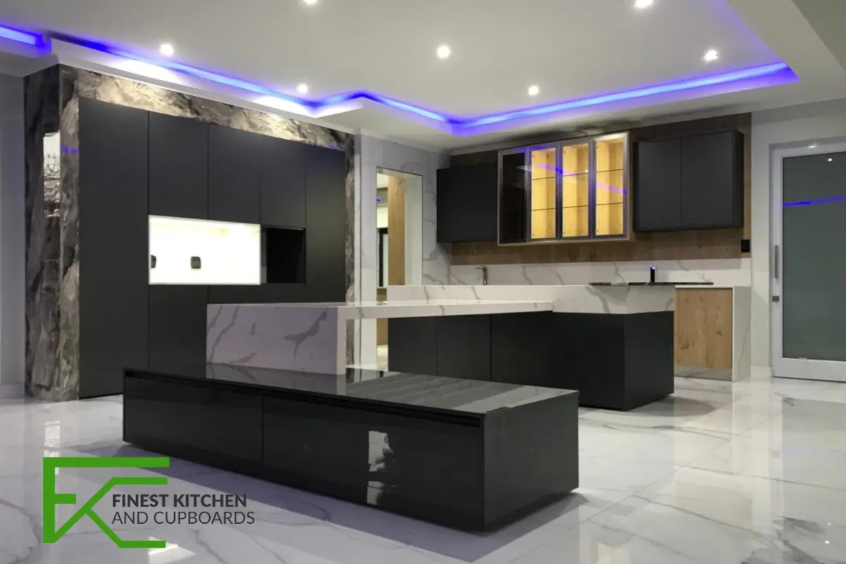 A dramatic FKC kitchen with a dark island, marble worktops, white gloss wall units and a recessed cove of coloured LED lighting.