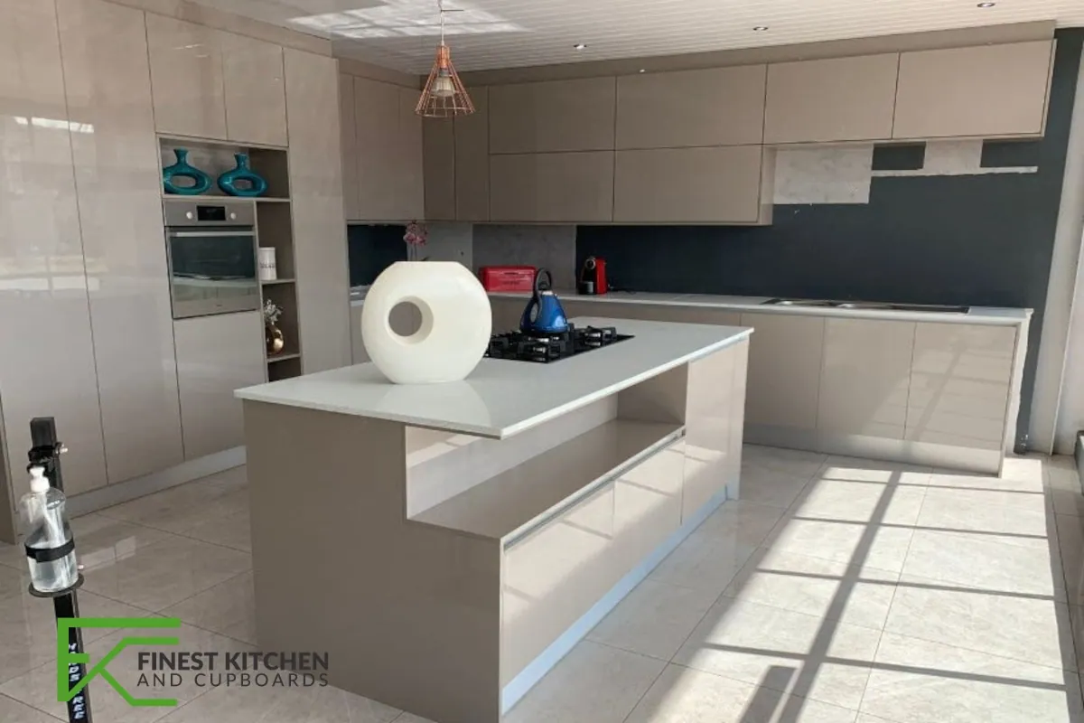 A cream FKC kitchen with a white-topped island, a single copper pendant light and a deep blue splashback.