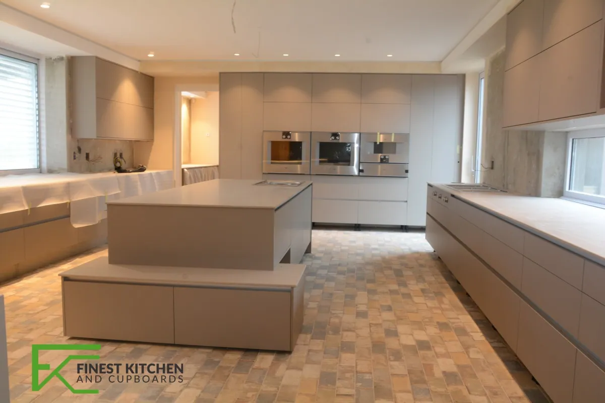 A long FKC galley kitchen with a cream island, white wall units and a wood-look tiled floor.